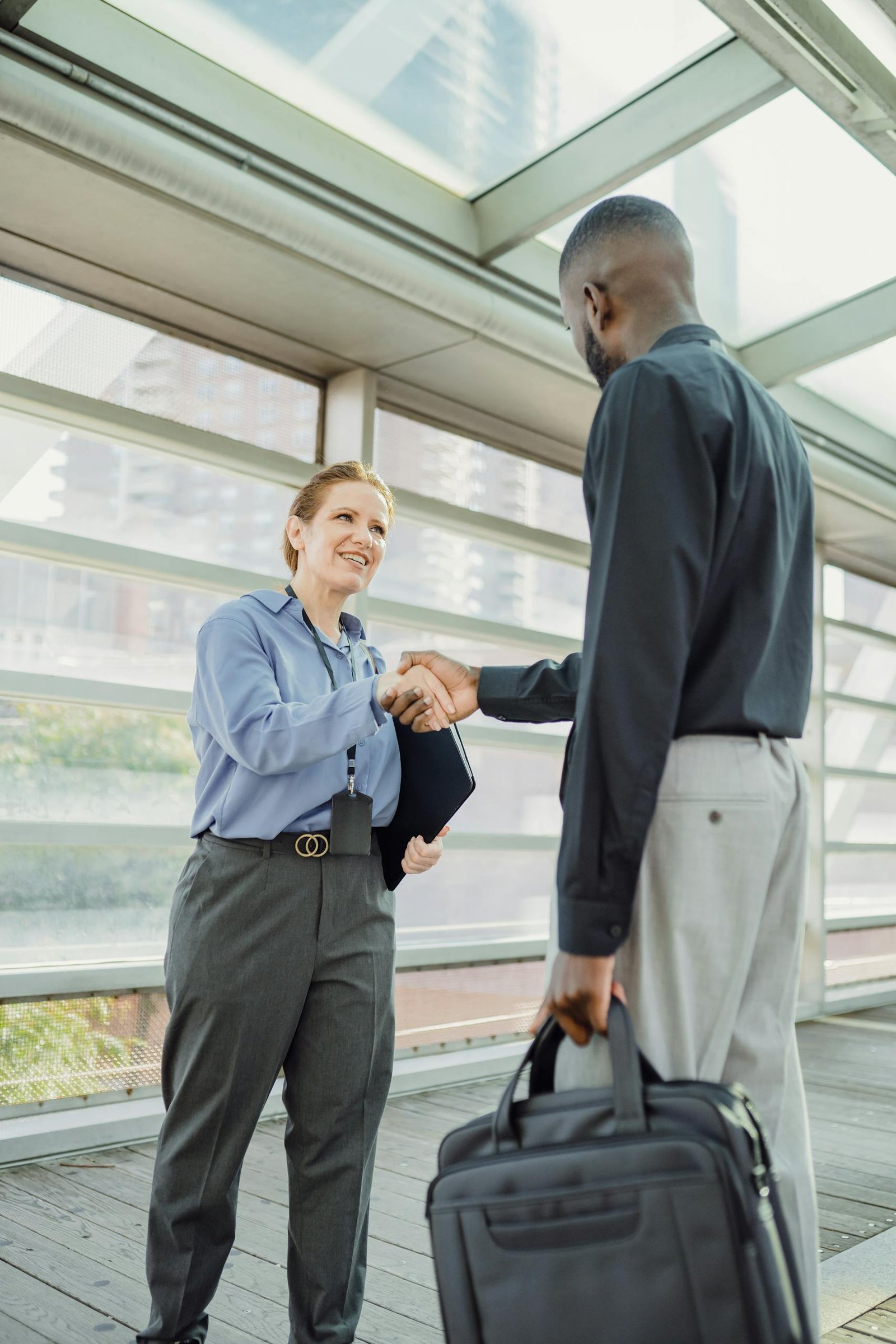 Two business professionals shaking hands in a modern cityscape setting, symbolizing cooperation.