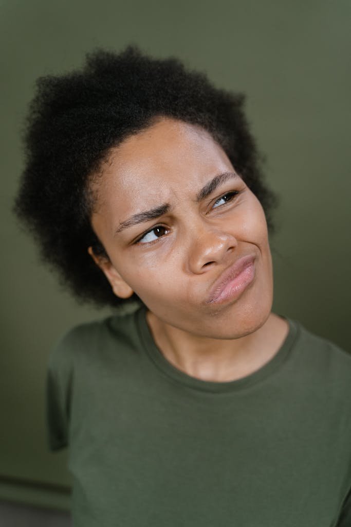 Young woman with afro hair showing a skeptical expression in a studio setting.