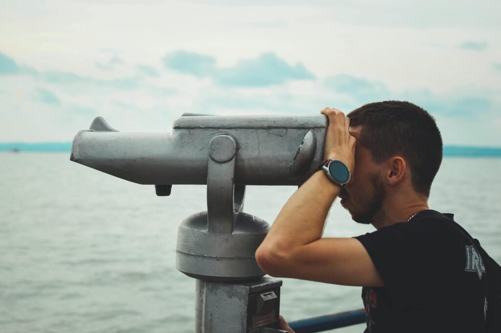 A man looks through binoculars over Lake Balaton in Siófok, Hungary, during the day.